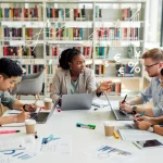 Graduate students discussing funding options in a university library.
