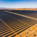 US Renewable Energy: 20 New Projects by 2030 Expansive solar farm with wind turbines, symbolising US renewable energy commitment.